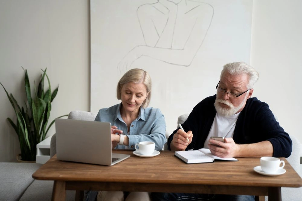 Senior couple reviewing retirement finances with a laptop and notebook