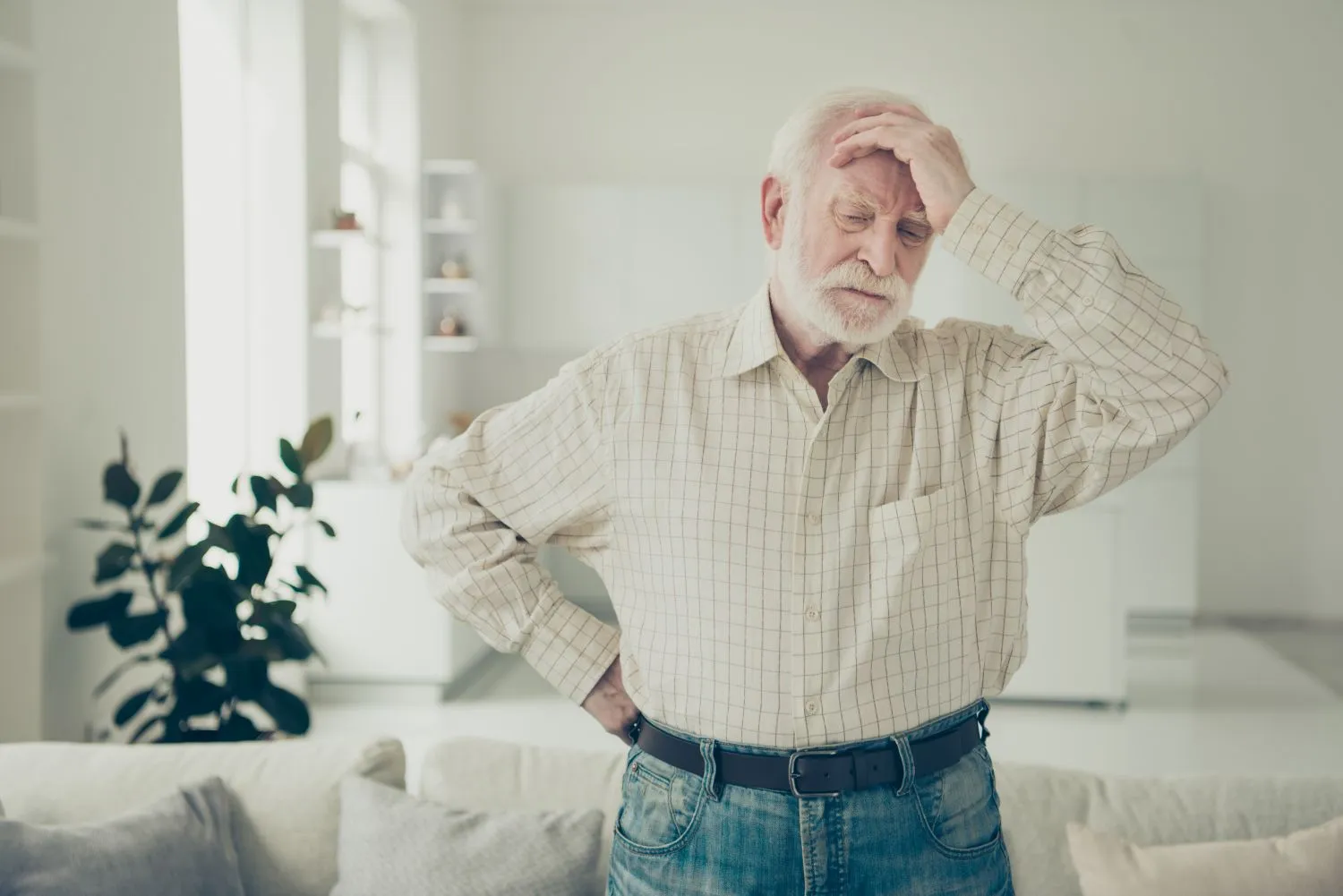 Anxious senior man standing at home with hand on head