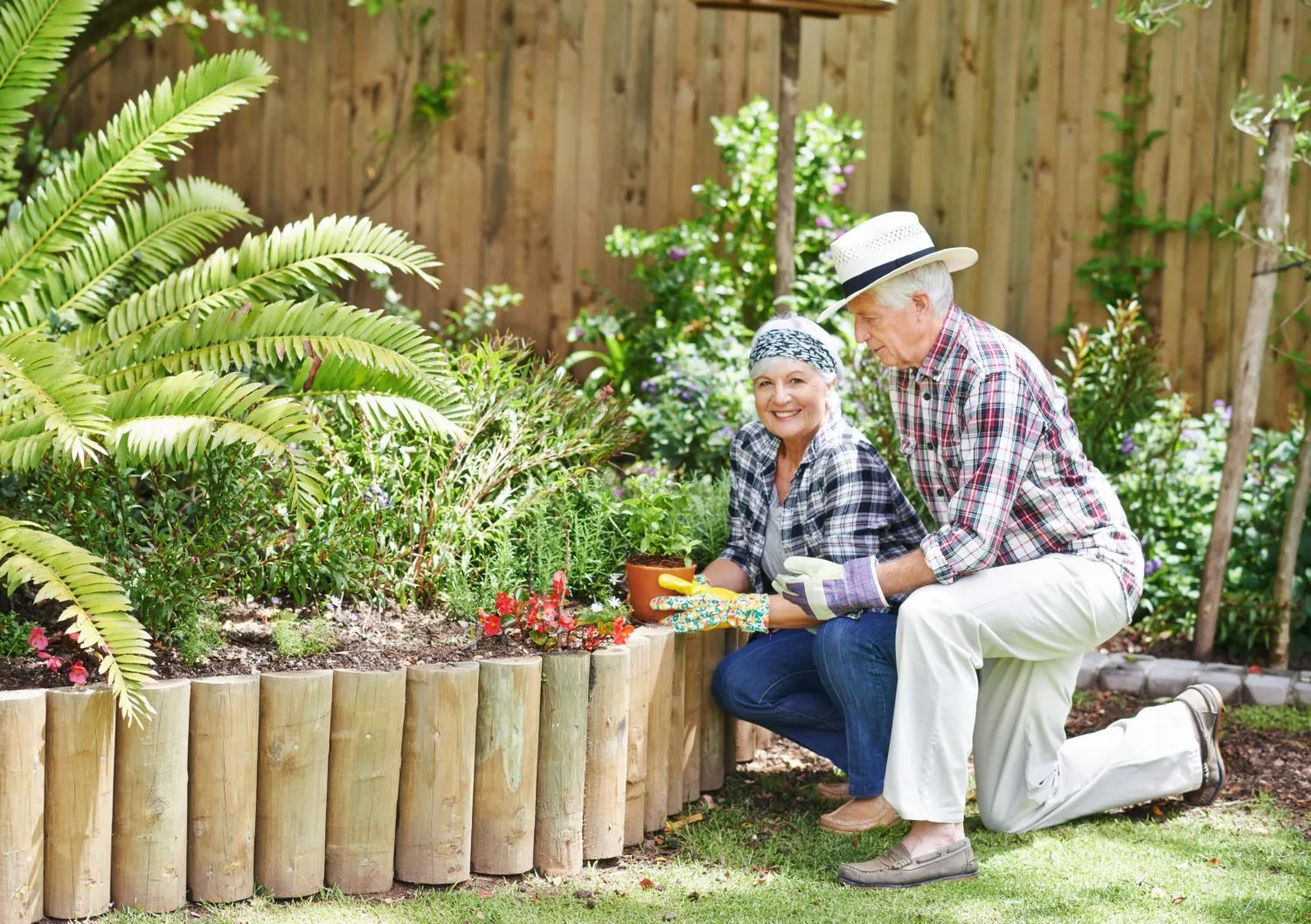 Senior couple gardening outdoors with flowers.